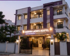 Sairam Ladies Hostel exterior at dusk with illuminated signage